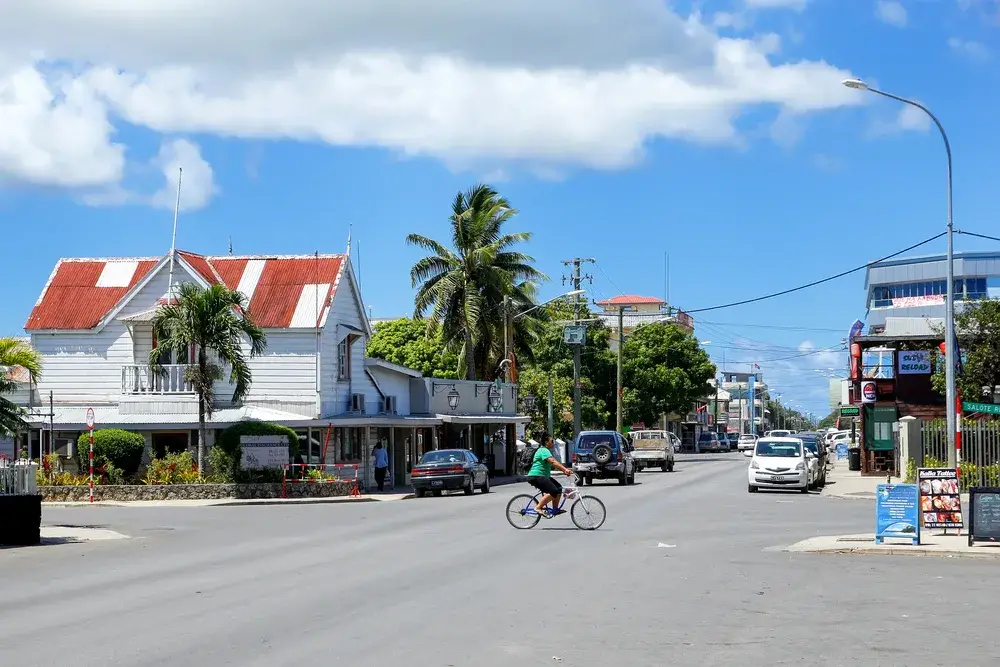 Image of a woman riding her bicycle across the street in Tonga for a guide on whether or not the country is safe to visit