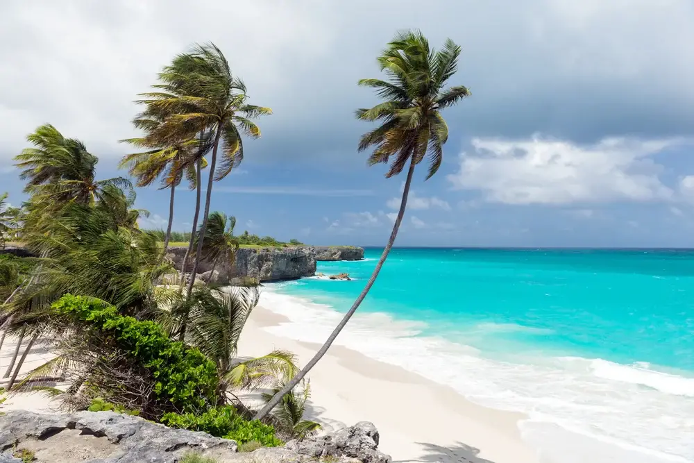 Tropical beach with a rain cloud over the ocean pictured during the worst time to visit Barbados
