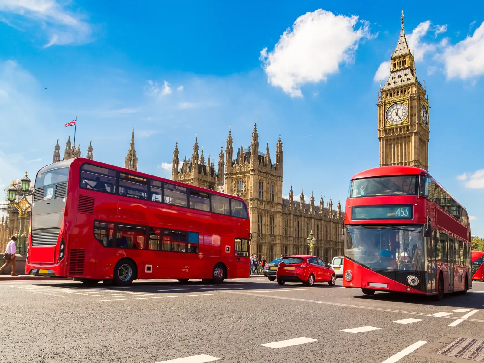 Red double-decker busses driving by Big Ben during the best time to visit London