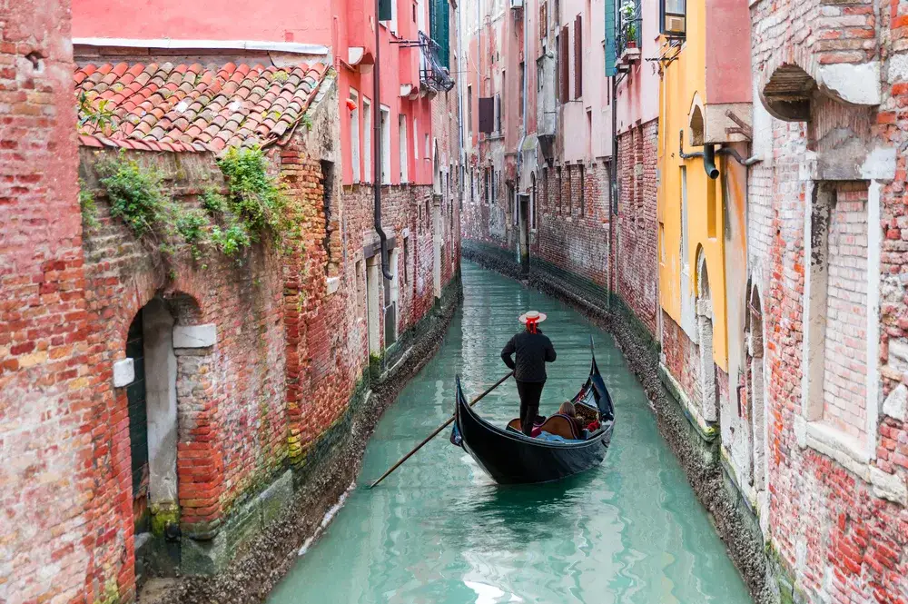 Venetian gondolier glides through the canals showing why you should visit Venice