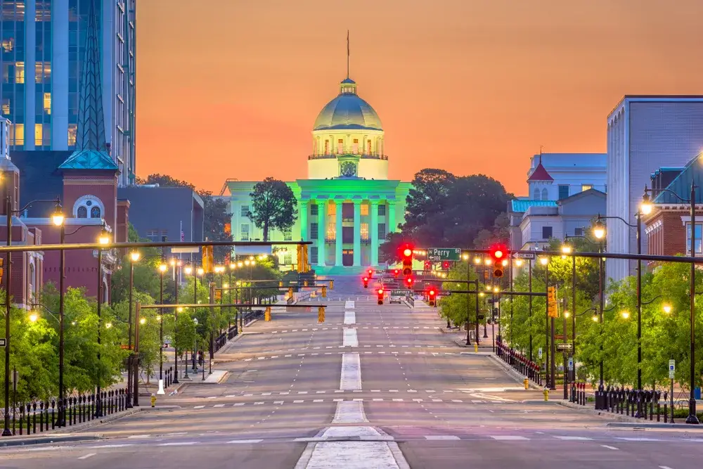 Beautiful dusk shot of a street in Montgomery, Alabama pictured with the city hall illuminated in green lights
