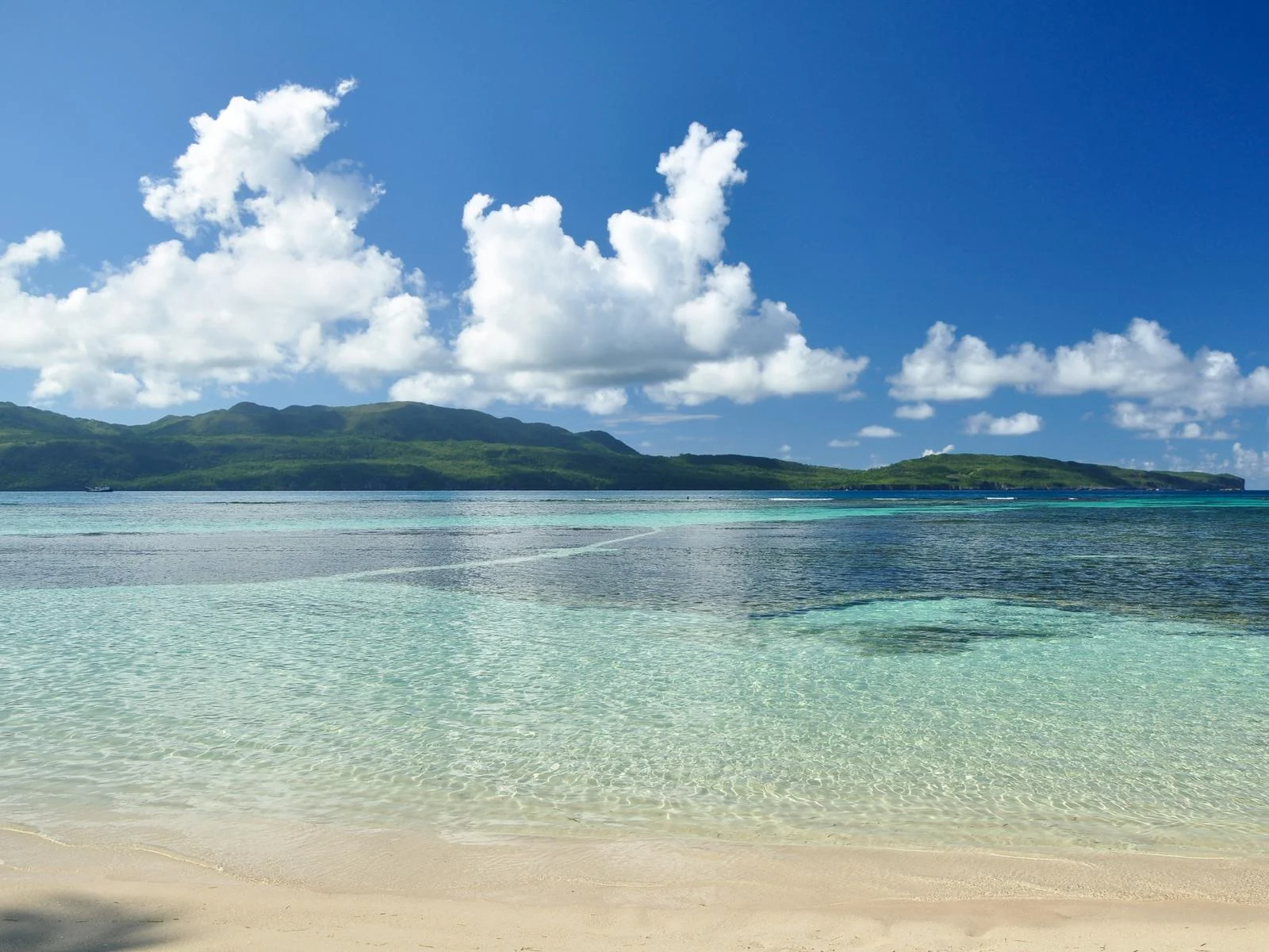 Photographed patches of clouds hovering over a mountain skyline and the crystalline water of La Playita in Las Galeras as a piece on the best beaches in the Dominican Republic