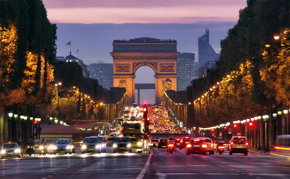 Nighttime view of Champs-Elysees with cars traveling for a piece asking Is Paris Safe