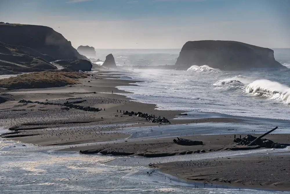 Waves crashing on the black sand beach of Sonoma during the best time to visit