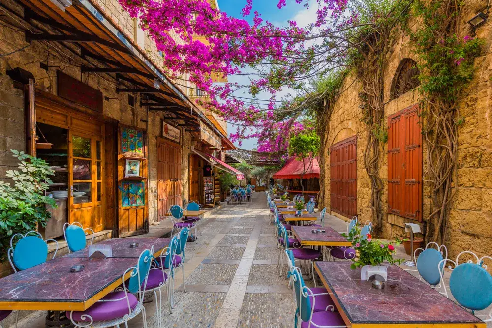 Old souks and restaurants on a narrow colorful street in Byblos during May, the best time to visit Lebanon, as flowers bloom