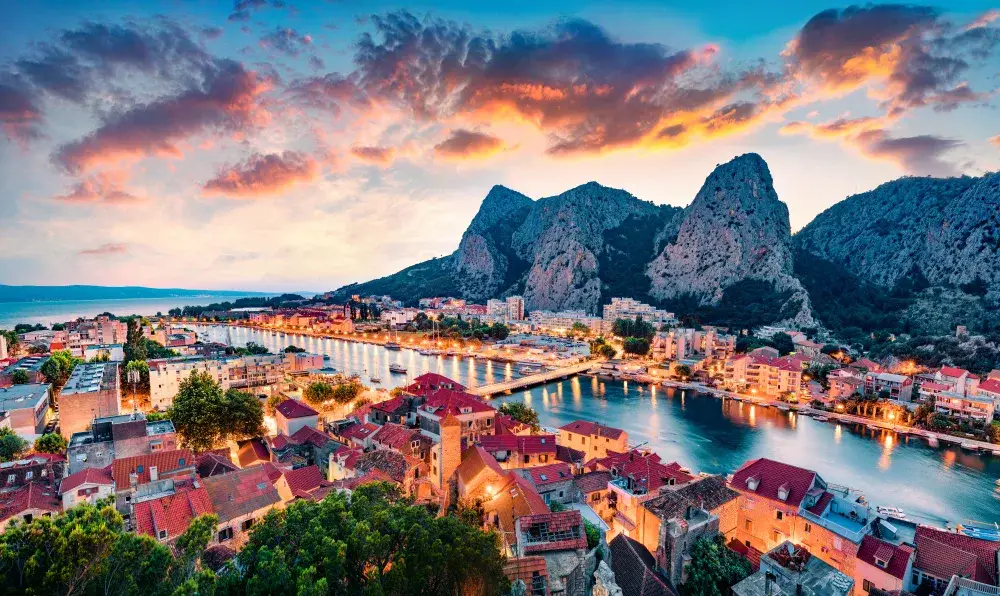 Sun setting over the old town of Dalmatia, which sits just below the large rock formations, on a calm dusk night