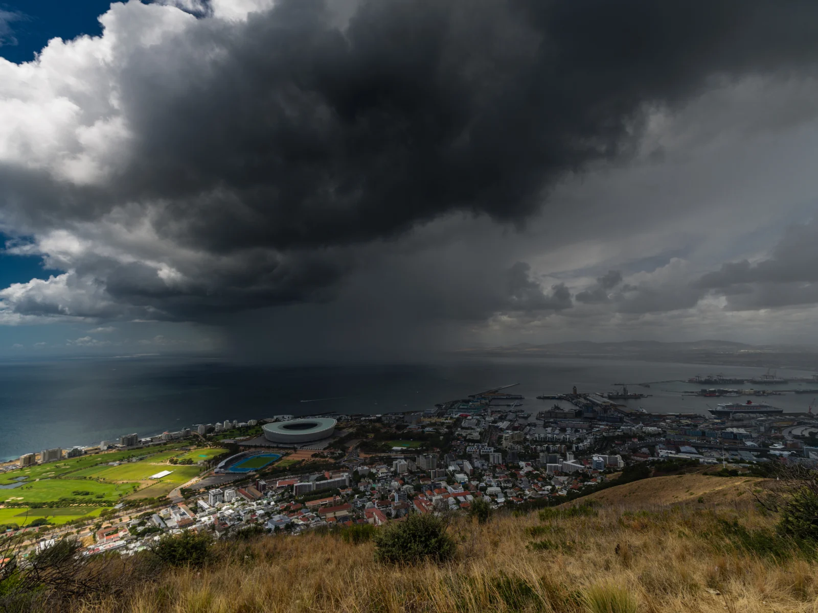 Cape town as seen from the hills with a storm cloud over the city and stadium during the worst time to visit South Africa