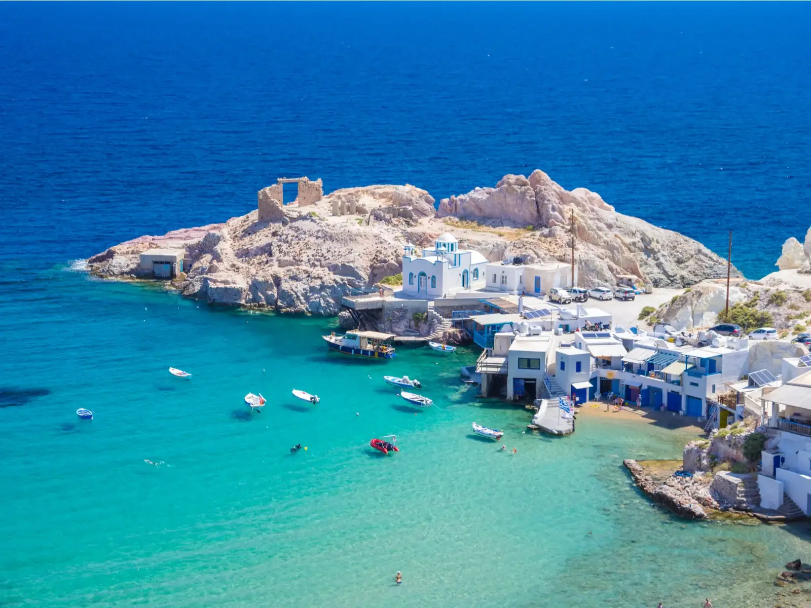 Aerial view of Firopotamos Village at Milos Island, a piece on the best islands in Greece to visit, where seen traditional fishermen's houses erected near at its coast and small fishing boats floating on crystal clear waters