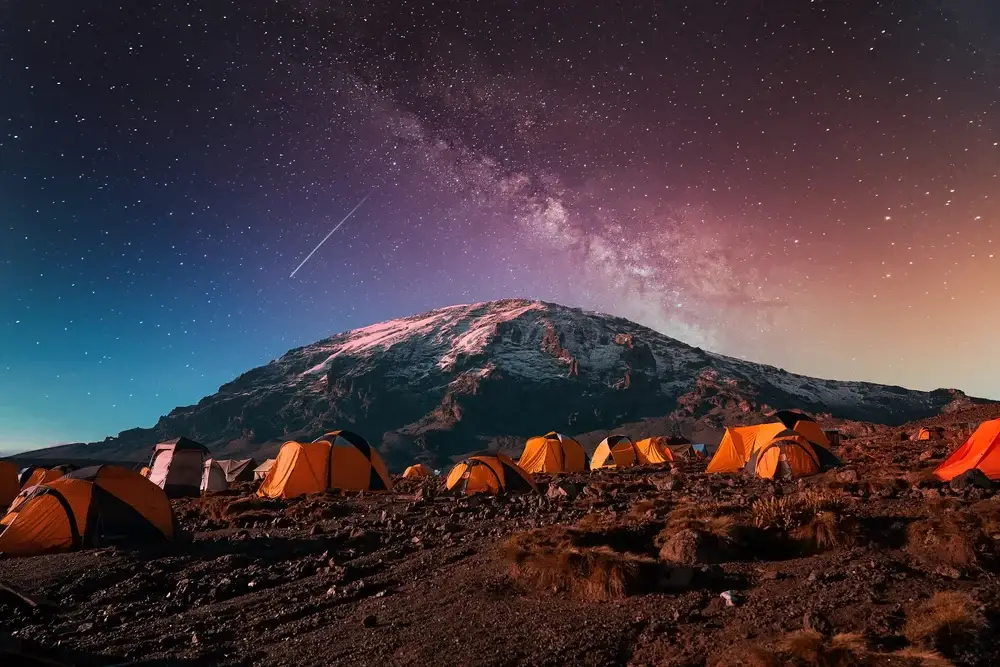 Milky Way view over Mount Kilimanjaro in the national park with yellow tents set up as a great spot for a honeymoon in Africa