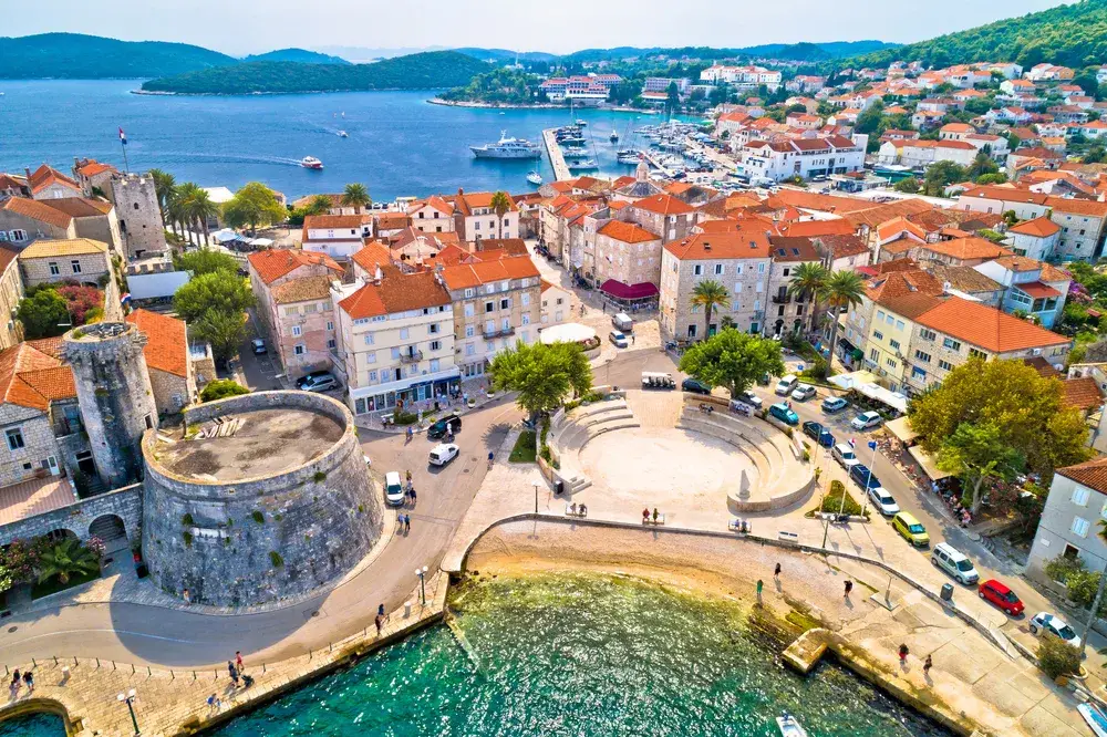 For a roundup of the best places to visit in Croatia, an aerial view of the harbor town of Korcula pictured on a sunny day