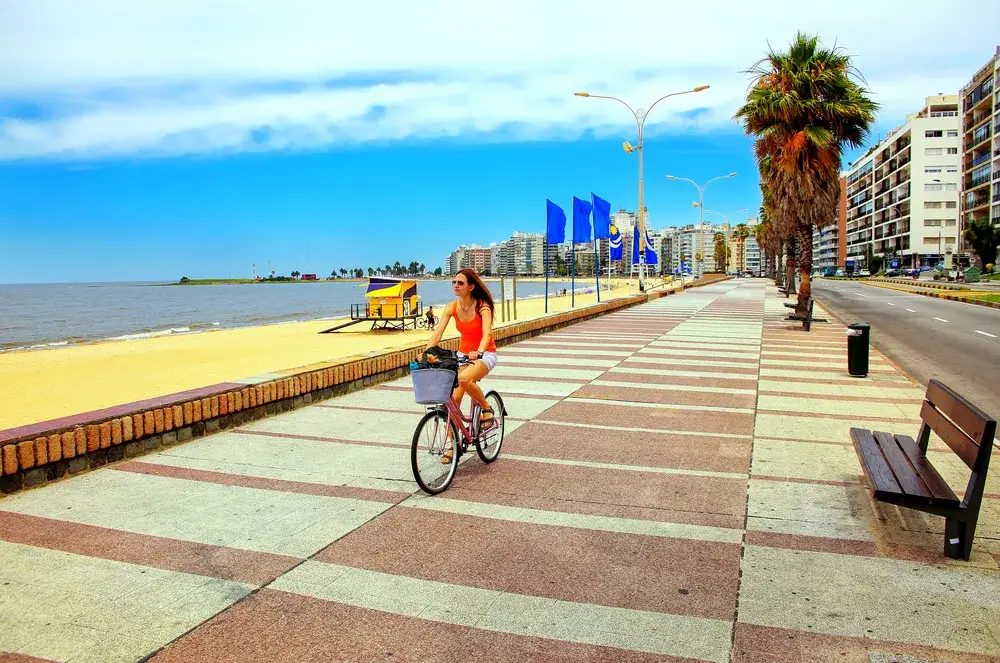 Woman in a red blouse riding a bicycle on the promenade in Montevideo for a guide to South American safety