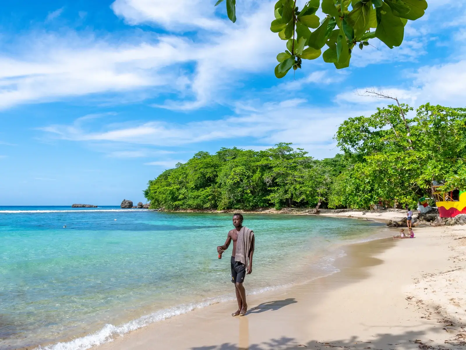 View of a guy walking on Winifred Beach, one of the best beaches in Jamaica, on a sunny day