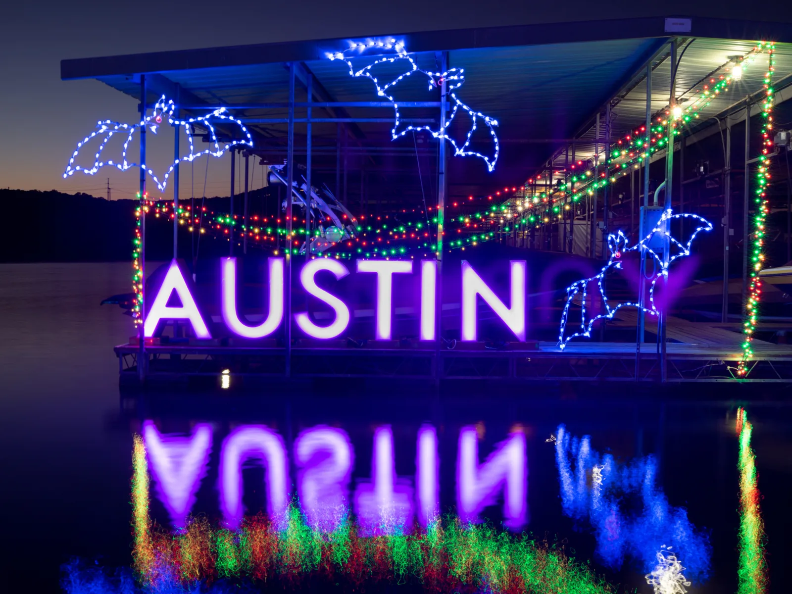 A lighted bat sign that says Austin overlooking a lake pictured during the best time to visit Austin