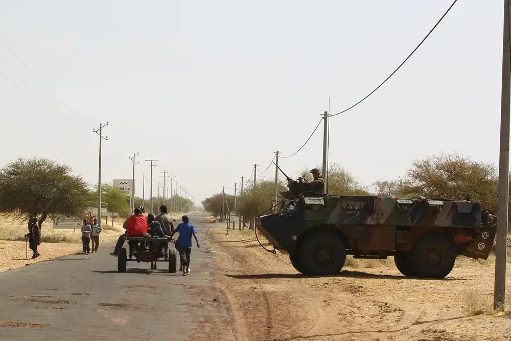 Armored troop carrier guarding a town while children walk by for a piece titled Is Mali Safe to Visit
