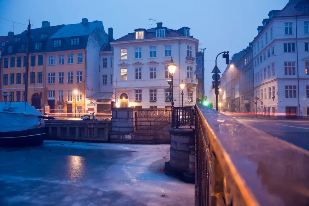 Cold winter morning in Copenhagen pictured with snow on the ground and an iced over canal during the worst time to visit Denmark