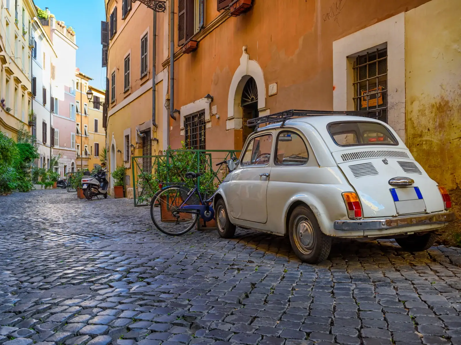 Cozy old street with a Fiat vehicle next to bikes during the least busy time to visit Rome