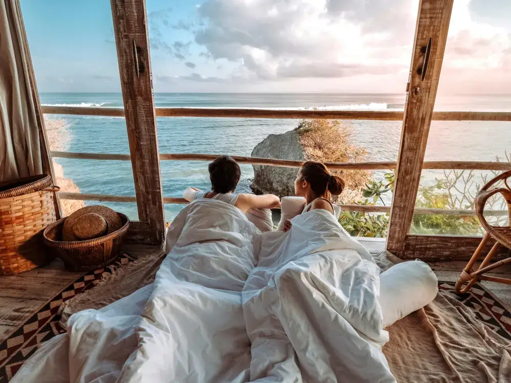 Couple gazing out over the ocean from their bed for a post on whether or not Bali is safe