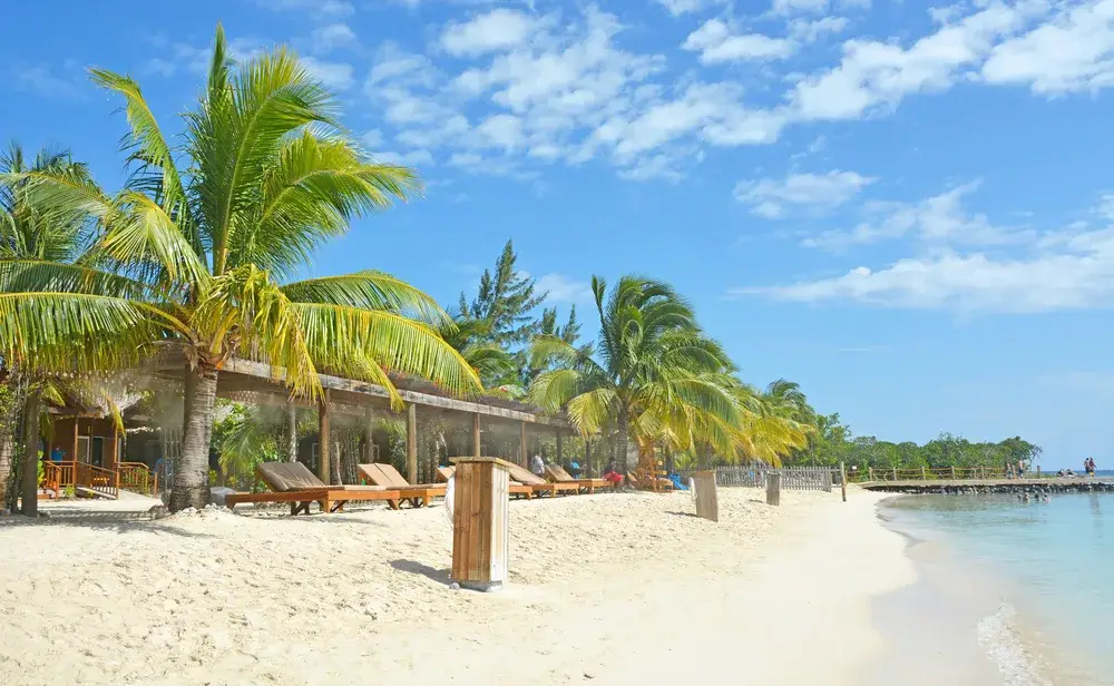 Mahogany Beach pictured during the least busy time to visit Roatan with nobody on the gorgeous white sand beach or the dock with rope railings